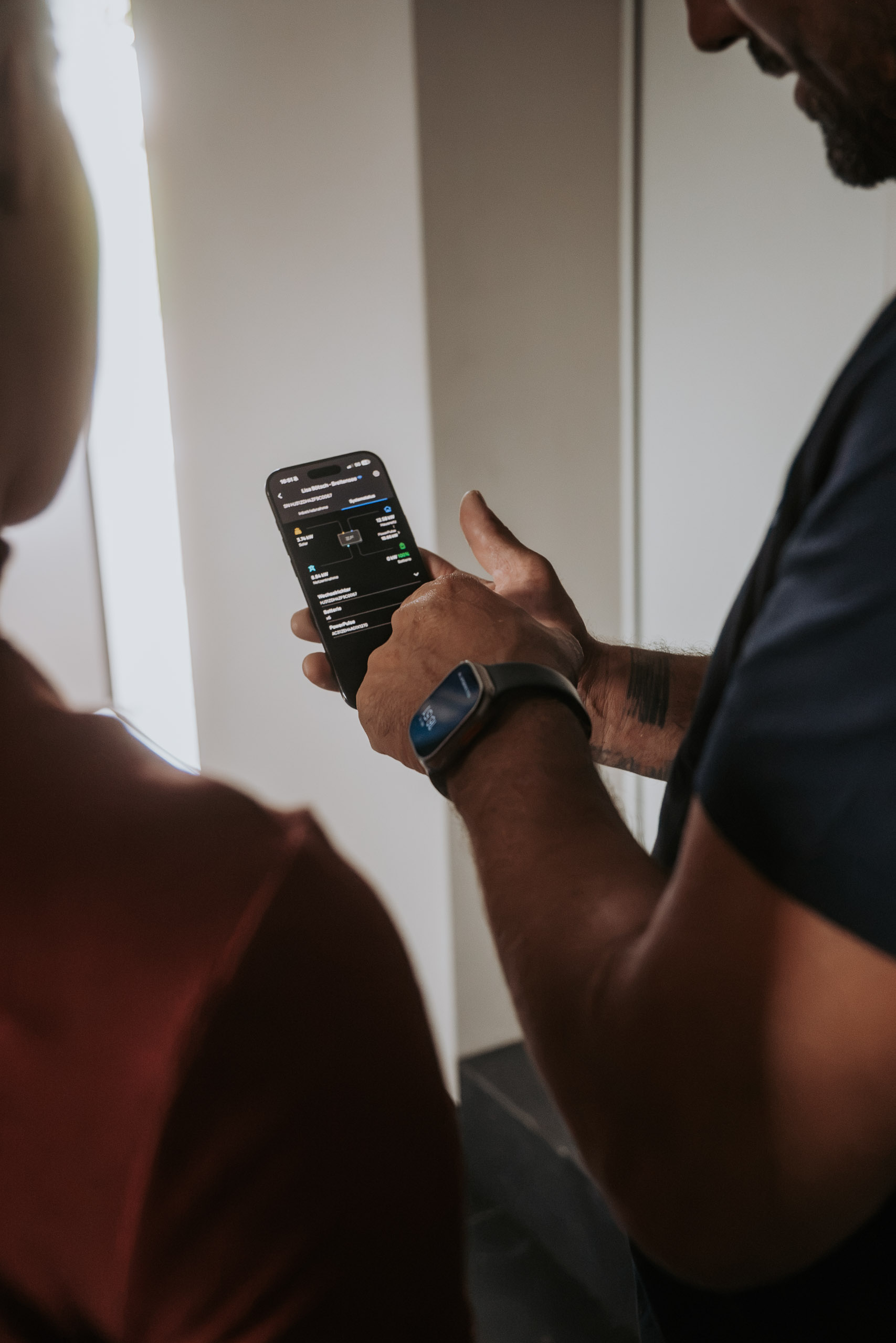 Techniker zeigt einer Kundin die Energie-Monitoring-App von EcoFlow auf einem Smartphone.